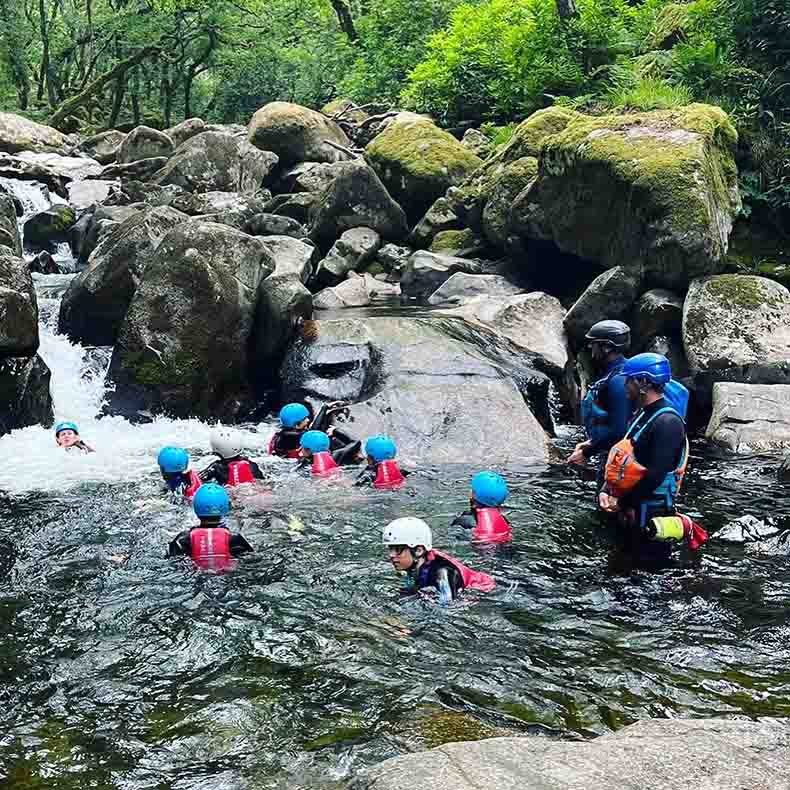 Children in the river with instructors