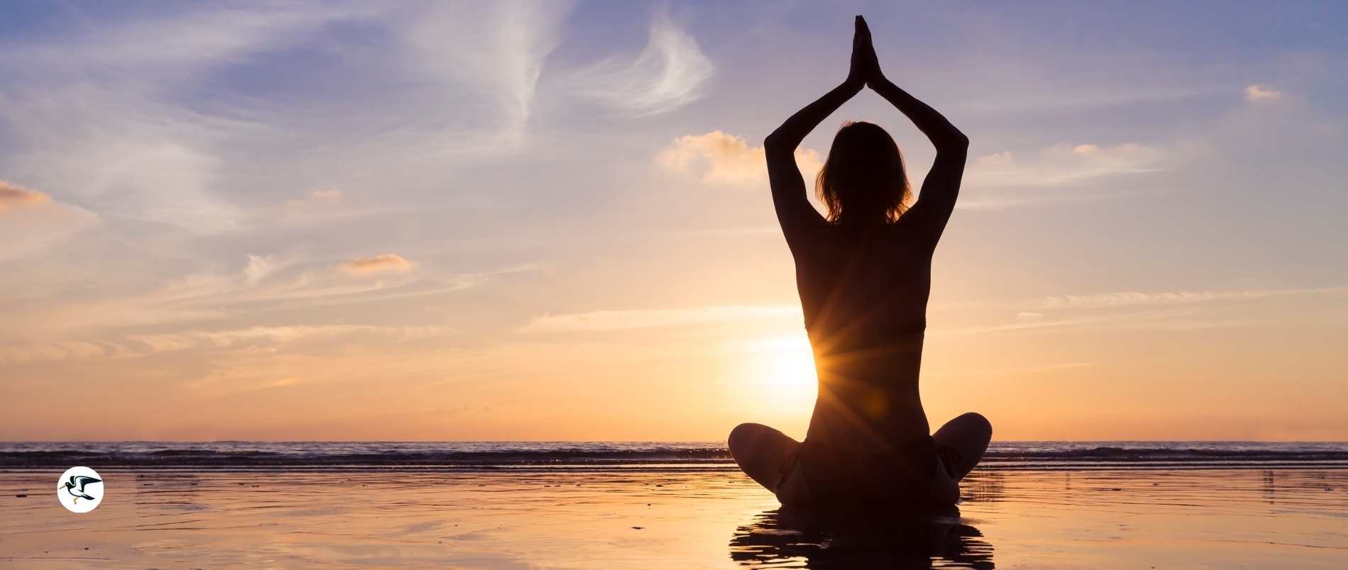 Person in yoga pose on the beach at sunset